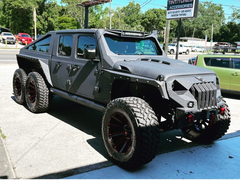 A jeep with large tires is parked in the parking lot.