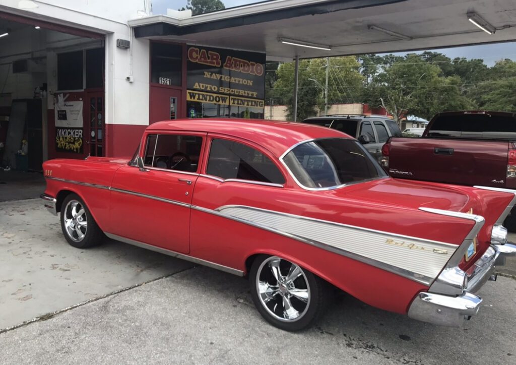 A red and white car parked in front of a gas station.